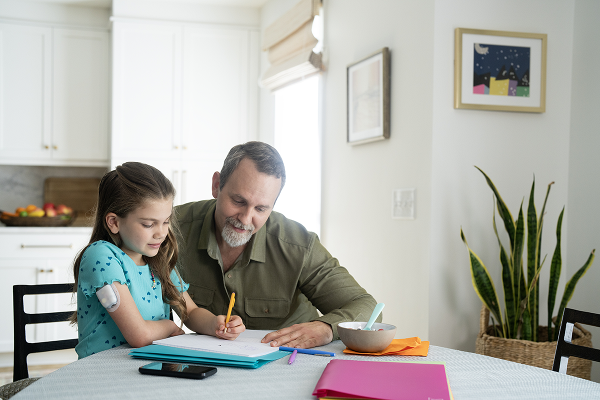 Father and daughter doing homework together in the kitchen