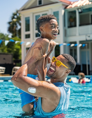 Father lifting son in a pool